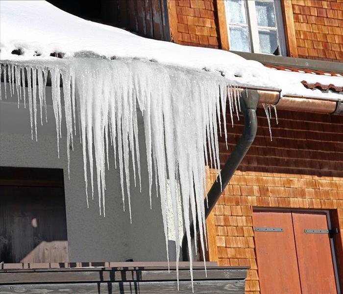 Image of icicles hanging off from the side of the roof of a home.